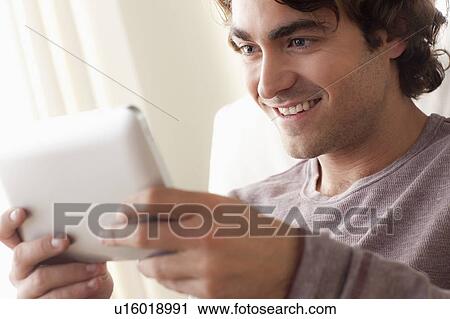 Smiling man using digital tablet View Large Photo Image Stock Image - Smiling man using digital tablet. Fotosearch