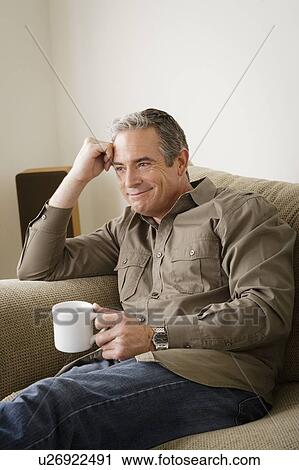 Stock Image - Smiling mature man holding mug. Fotosearch