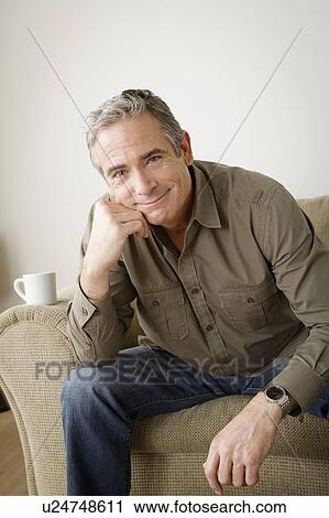 Smiling mature man sitting on sofa View Large Photo Image Stock Image - Smiling mature man sitting on sofa. Fotosearch