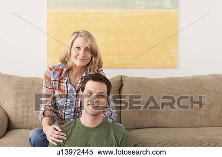 Stock Photography - Smiling mid adult couple sitting on sofa. Fotosearch