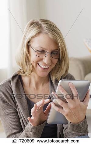 Stock Photo - Smiling mid adult woman using digital tablet. Fotosearch