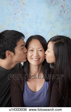 Stock Photograph - Smiling mother kissed by her children. Fotosearch