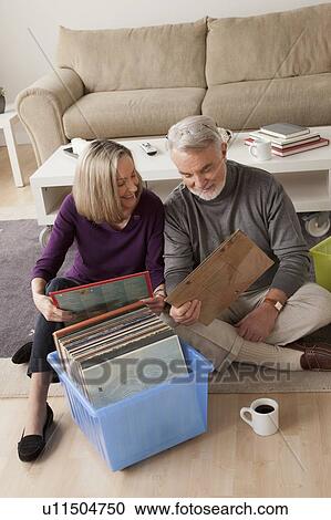 Smiling senior couple looking at vinyl's in living room View Large Photo Image Stock Image - Smiling senior couple looking at vinyl's in living room. Fotosearch