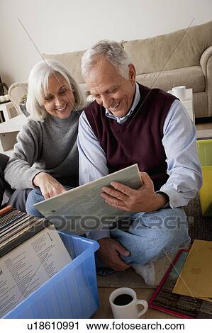 Smiling senior couple looking at vinyl's in living room View Large Photo Image Stock Image - Smiling senior couple looking at vinyl's in living room. Fotosearch