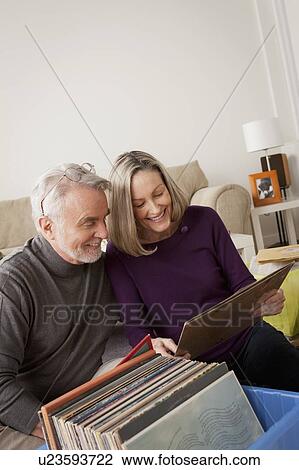 Smiling senior couple looking at vinyl's in living room View Large Photo Image Stock Image - Smiling senior couple looking at vinyl's in living room. Fotosearch