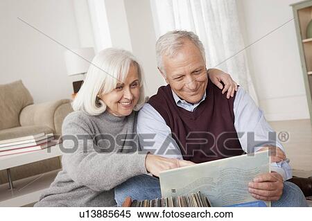 Smiling senior couple looking at vinyl's in living room View Large Photo Image Stock Photography - Smiling senior couple looking at vinyl's in living room. Fotosearch
