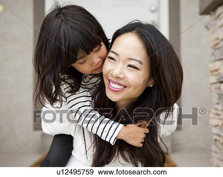 Stock Photo - Smiling woman embracing by her daughter (4-5). Fotosearch