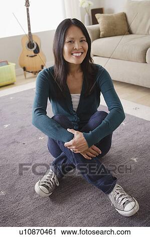 Stock Image - Smiling woman sitting on floor. Fotosearch