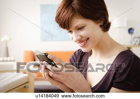 Smiling woman using mobile at home View Large Photo Image Stock Photo - Smiling woman using mobile at home. Fotosearch