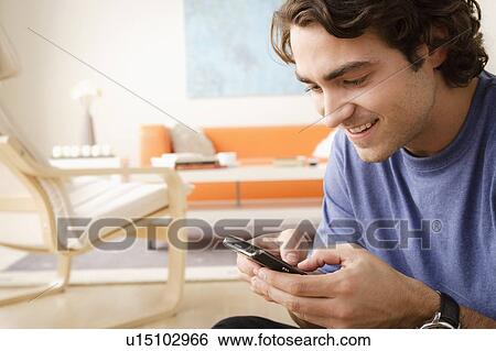 Smiling woman using mobile at home View Large Photo Image Stock Photograph - Smiling woman using mobile at home. Fotosearch