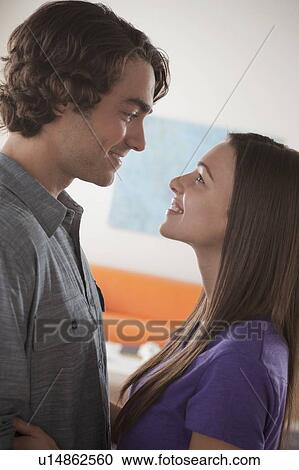Smiling young couple looking at each other View Large Photo Image Stock Image - Smiling young couple looking at each other. Fotosearch