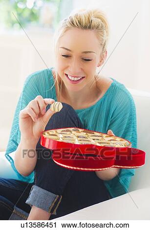 Smiling young woman eating chocolates View Large Photo Image Stock Image - Smiling young woman eating chocolates. Fotosearch