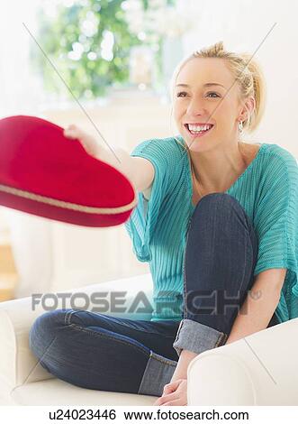 Stock Photograph - Smiling young woman holding box of chocolates in heart shape. Fotosearch