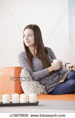 Smiling young woman reading on sofa View Large Photo Image Stock Photography - Smiling young woman reading on sofa. Fotosearch