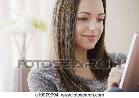 Smiling young woman using digital tablet View Large Photo Image Picture - Smiling young woman using digital tablet . Fotosearch
