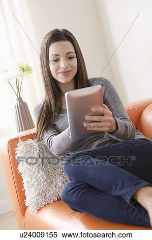 Smiling young woman using digital tablet on sofa View Large Photo Image Stock Photography - Smiling young woman using digital tablet on sofa. Fotosearch