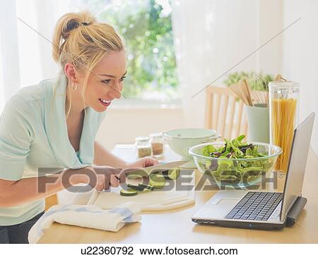 Smiling young woman using laptop in kitchen View Large Photo Image Stock Image - Smiling young woman using laptop in kitchen. Fotosearch