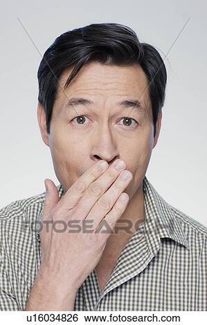 Studio portrait of mature man covering mouth View Large Photo Image Stock Photograph - Studio portrait of mature man covering mouth. Fotosearch