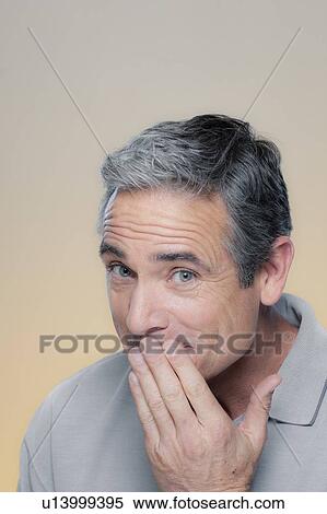Studio Portrait of mature man covering mouth with hand View Large Photo Image Stock Photography - Studio Portrait of mature man covering mouth with hand. Fotosearch