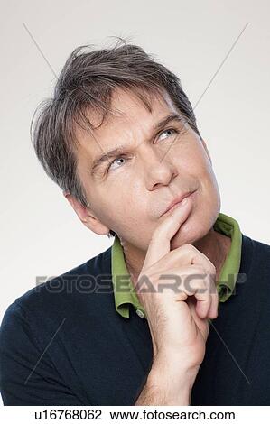 Stock Image - Studio portrait of mature man with hand on chin. Fotosearch