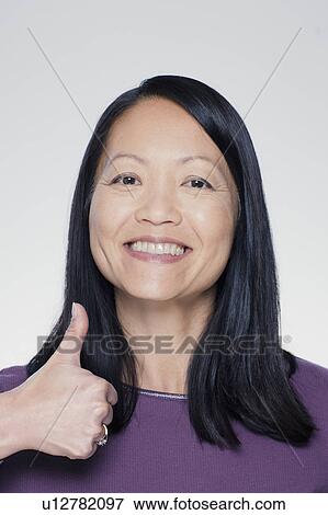 Studio portrait of mature woman showing thumbs up sign View Large Photo Image Stock Photo - Studio portrait of mature woman showing thumbs up sign. Fotosearch