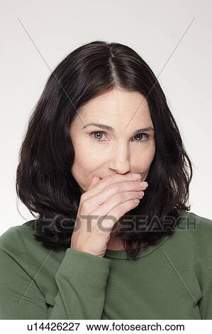 Studio portrait of mature woman covering mouth View Large Photo Image Stock Photo - Studio portrait of mature woman covering mouth. Fotosearch
