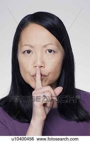 Studio portrait of mature woman with finger on lips View Large Photo Image Stock Photograph - Studio portrait of mature woman with finger on lips. Fotosearch