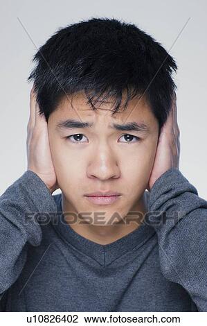 Studio portrait of young man covering ears View Large Photo Image Stock Image - Studio portrait of young man covering ears. Fotosearch