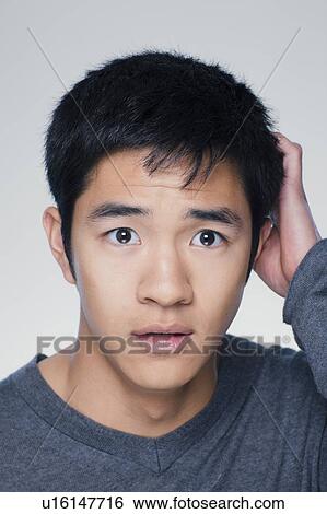 Studio portrait of young man scratching head View Large Photo Image Stock Photograph - Studio portrait of young man scratching head. Fotosearch