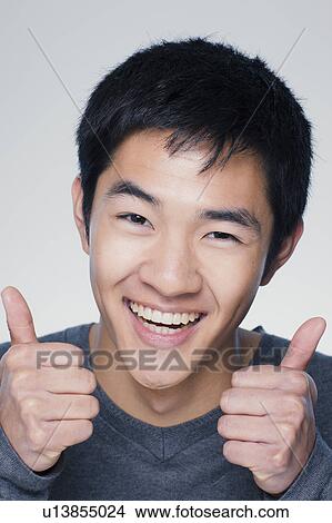 Picture - Studio portrait of young man showing thumbs up sign. Fotosearch