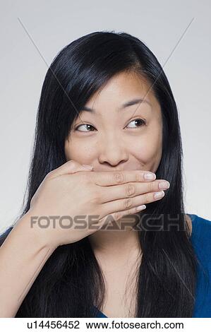 Studio portrait of young woman covering mouth View Large Photo Image Stock Image - Studio portrait of young woman covering mouth. Fotosearch