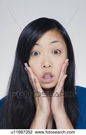 Stock Image - Studio portrait of young woman with head in hands. Fotosearch