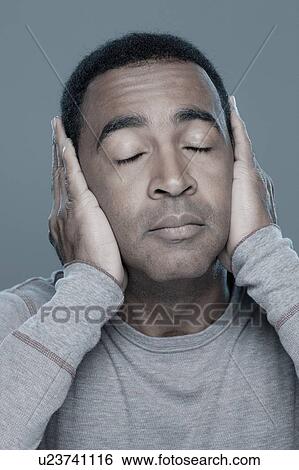 Stock Photograph - Studio shot of mature man covering ears. Fotosearch