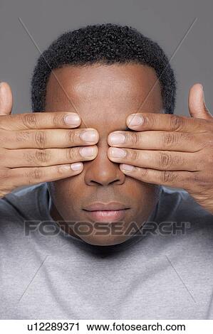 Studio shot of mid adult man covering eyes View Large Photo Image Stock Image - Studio shot of mid adult man covering eyes. Fotosearch