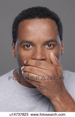 Stock Image - Studio shot of mid adult man covering lips. Fotosearch