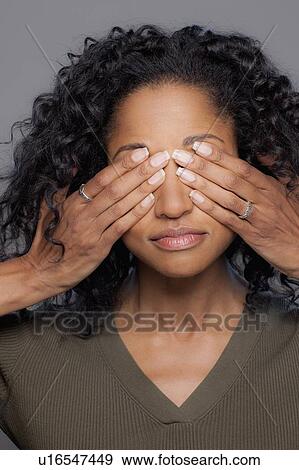 Stock Photo - Studio shot of mid adult woman covering eyes. Fotosearch