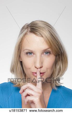 Studio shot of mid adult woman with finger on lips View Large Photo Image Stock Image - Studio shot of mid adult woman with finger on lips. Fotosearch