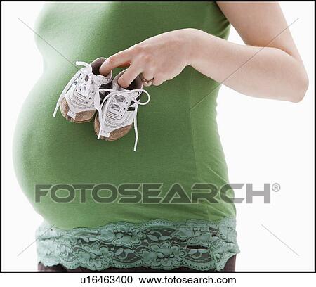Studio Shot of mid section of pregnant woman holing baby booties View Large Photo Image Stock Image - Studio Shot of mid section of pregnant woman holing baby booties. Fotosearch