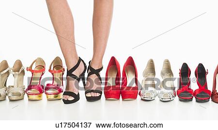 Stock Photo - Studio shot of row of shoes, woman wearing one of them. Fotosearch