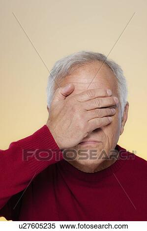 Stock Photography - Studio shot of senior man covering eyes. Fotosearch