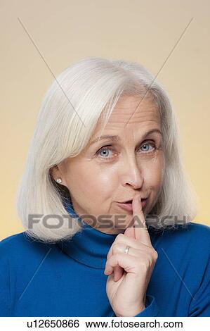 Studio shot of senior woman with finger on her lips View Large Photo Image Stock Photograph - Studio shot of senior woman with finger on her lips. Fotosearch