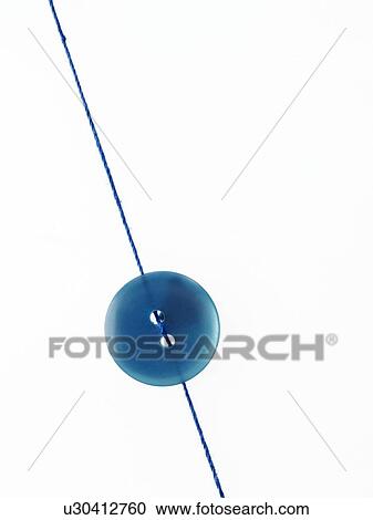 Stock Image - Studio shot of single blue button on thread. Fotosearch