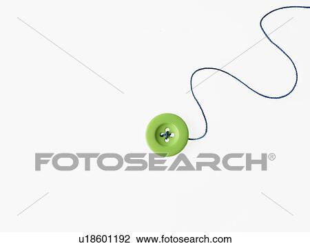 Stock Image - Studio shot of single green button on thread. Fotosearch