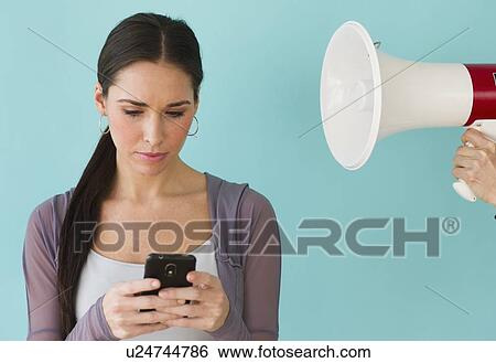Studio shot of woman texting and ignoring voice from bullhorn View Large Photo Image Stock Photograph - Studio shot of woman texting and ignoring voice from bullhorn. Fotosearch