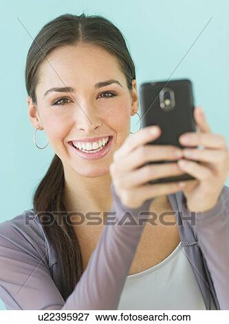 Stock Photo - Studio shot of woman using smart phone. Fotosearch