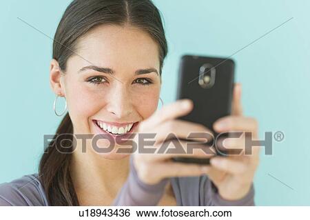 Stock Photograph - Studio shot of woman using smart phone. Fotosearch