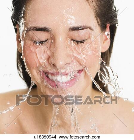 Picture - Studio shot of woman with splash of water on face. Fotosearch