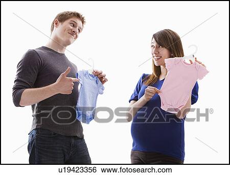 Stock Photograph - Studio Shot of young couple holding onesie. Fotosearch