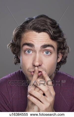Studio shot of young man with finger on his lips View Large Photo Image Stock Photography - Studio shot of young man with finger on his lips. Fotosearch