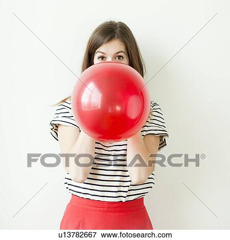 Studio shot of young woman blowing balloon View Large Photo Image Stock Photo - Studio shot of young woman blowing balloon. Fotosearch